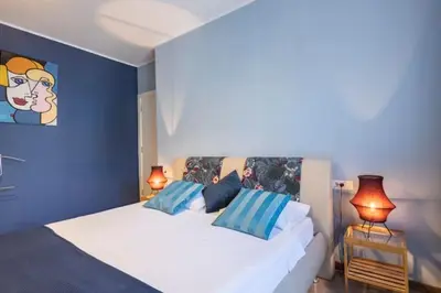 a bedroom with a white bed with blue walls and two lamps at Indigo Apartment in Belgrade