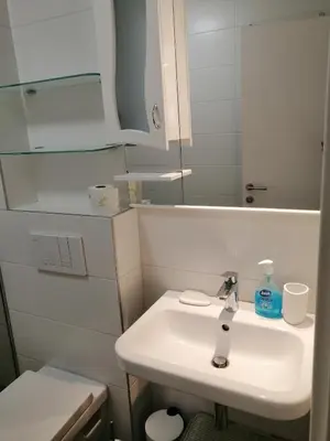 a white bathroom with a sink and a mirror at Anejo A Blok in Novi Beograd