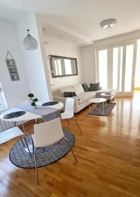 a living room with a couch and a table and chairs at Belville Delta City apartment, free parking in Belgrade