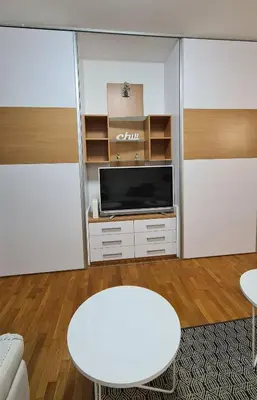 a living room with a tv and a white stool at Belville Delta City apartment, free parking in Belgrade