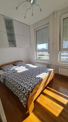 a bedroom with a bed in a room with two windows at Belville Delta City apartment, free parking in Belgrade