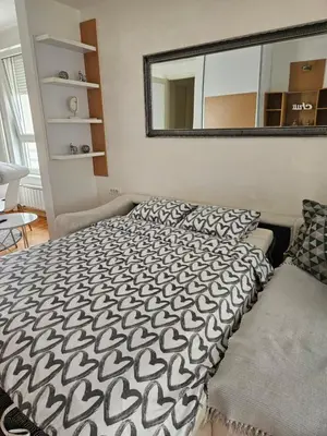 a bed with a black and white comforter and a mirror at Belville Delta City apartment, free parking in Belgrade