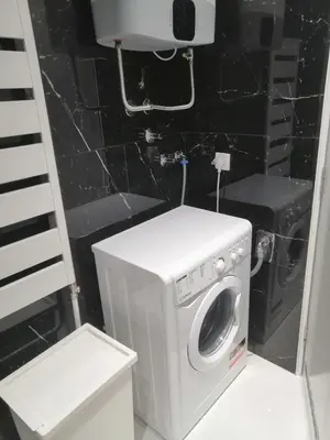 a washing machine in a bathroom with a black wall at Anejo Belvil in Novi Beograd