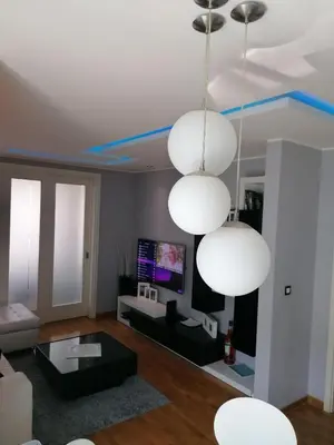 a living room with three lights hanging from the ceiling at Apartment Belville, Suncokret 34 in Novi Beograd