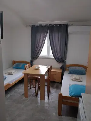 a room with two beds and a table and a window at LIBERO APARTMANI in Surčin