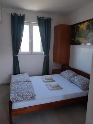 a bedroom with a bed and a window with blue curtains at LIBERO APARTMANI in Surčin