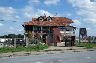 a house with a tiled roof on the side of the street at Motel Imperija in Ub