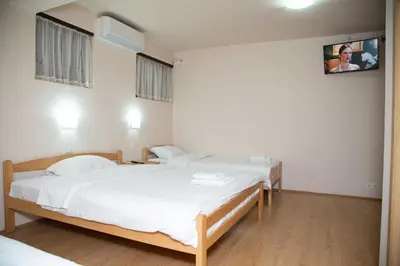 a bedroom with two beds and a tv on the wall at Motel Imperija in Ub