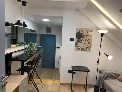 a kitchen and living room with a table and a blue door at CITY CENTER Apartment in Belgrade