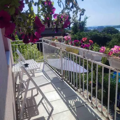 a balcony with a chair and flowers at Lux Apartmans-VILA MALI RAJ in Udovice
