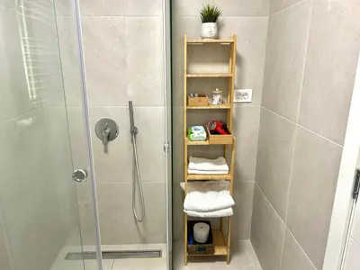 a bathroom with a shower with towels on a shelf at Bulevard Luxury Suites in Belgrade