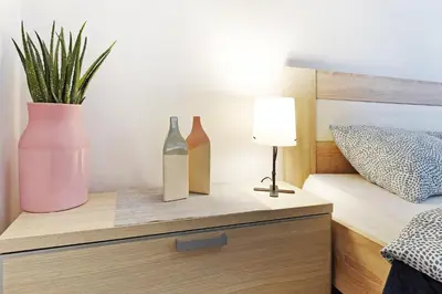two vases and a plant on a night stand next to a bed at Lion Apartment - Belgrade in Belgrade
