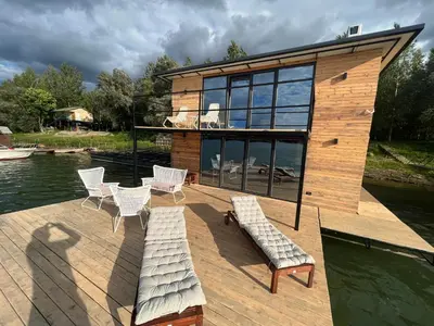 a house on a wooden deck with chairs and water at Splav Shoom in Ostružnica