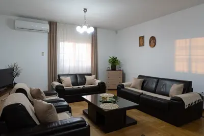 a living room with black leather couches and a table at Green Art House in Kovilovo