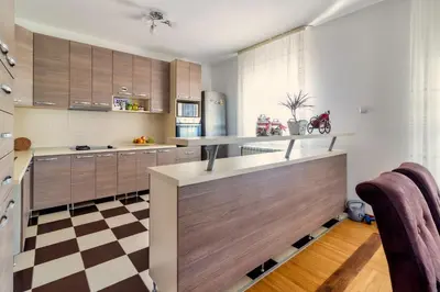 a kitchen with wooden cabinets and a checkered floor at Green Art House in Kovilovo
