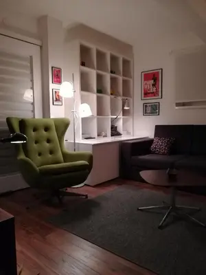 a living room with a green chair and a couch at Gray apartment in Čukarica