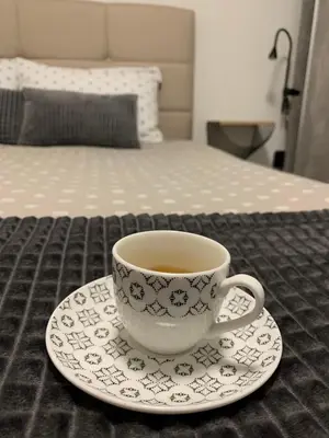 a cup of coffee sitting on a plate on a bed at DM apartman Beograd in Vračar (historical)