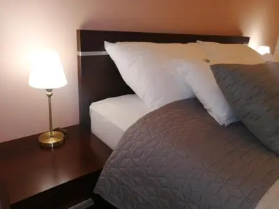 a bed with white pillows and a table with a lamp at Vila Vidikovac Arandjelovac in Arandjelovac