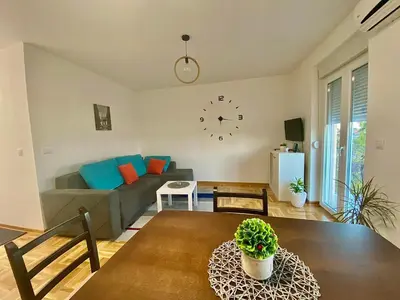a living room with a couch and a clock on the wall at BellaVista apartman in Stara Pazova
