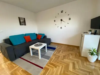 a living room with a couch and a clock on the wall at BellaVista apartman in Stara Pazova