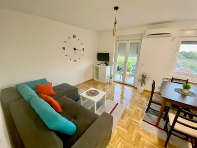 a living room with a couch and a clock on the wall at BellaVista apartman in Stara Pazova
