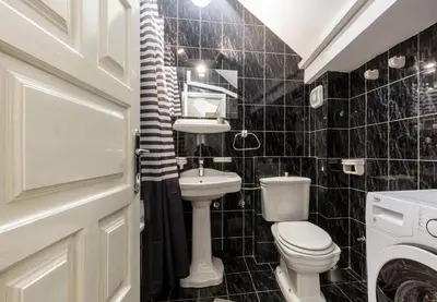 a black tiled bathroom with a toilet and a sink at Centrum in Belgrade