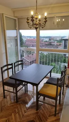 a dining room table and chairs with a large window at Apartments near city center in Belgrade