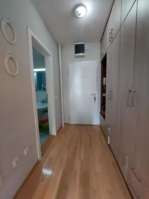an empty hallway with a white door and wooden floors at Xenia apartments in Belgrade