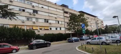 a street with cars parked in front of a large building at Spacious Loft with one bedroom and a big terrace in Belgrade