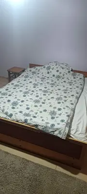 a bed with a blue and white blanket on it at Happy Home in Starčevo