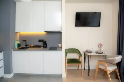 a kitchen with white cabinets and a table with a green chair at Belgrade Waterfront Metropolitan in Belgrade