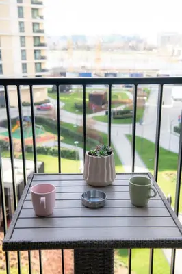 a wooden table with two cups on a balcony at Belgrade Waterfront Metropolitan in Belgrade