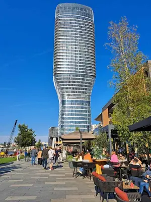 a tall building with people sitting at tables in front of it at Belgrade Waterfront Metropolitan 2 in Belgrade