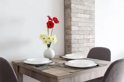 a wooden table with plates and flowers in a vase at Apartman Nelly - Fontana in Fontana