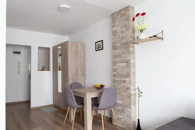 a dining room with a table and chairs and a brick wall at Apartman Nelly - Fontana in Fontana