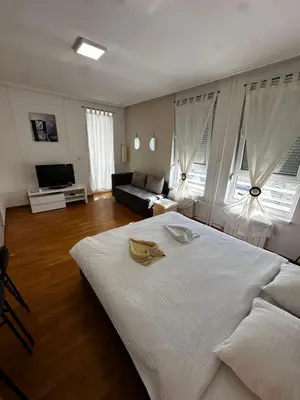 a bedroom with a large white bed and a living room at Nevena Belville Apartments in Belgrade