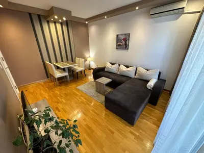 a living room with a black couch and a table at Nevena Belville Apartments in Belgrade