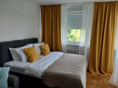 a bedroom with a bed with yellow curtains and a window at Dolce vita 1 in Belgrade