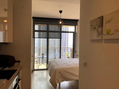 a bedroom with a bed and a door to a balcony at Cozy Belgrade Waterfront studio with Murphy bed in Belgrade