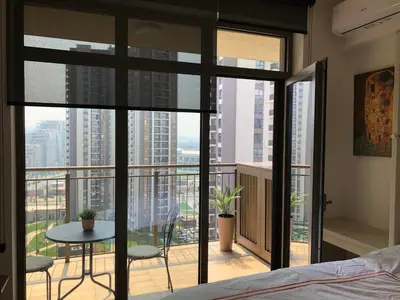 a bedroom with a bed and a balcony with a table and chairs at Cozy Belgrade Waterfront studio with Murphy bed in Belgrade