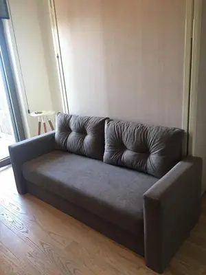 a grey couch in a room with a window at Cozy Belgrade Waterfront studio with Murphy bed in Belgrade