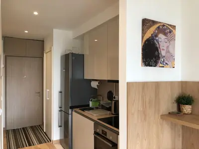 a kitchen with white cabinets and a counter top at Cozy Belgrade Waterfront studio with Murphy bed in Belgrade
