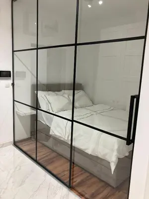 a bedroom with a glass partition with a bed at K2 Apartmani in Belgrade