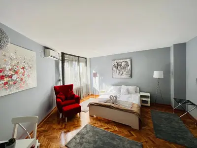 a bedroom with a bed and a red chair at Iskra Apartment in Belgrade