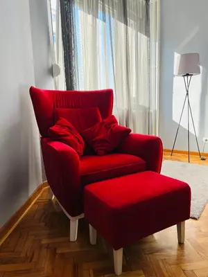 a red chair and ottoman in a living room at Iskra Apartment in Belgrade