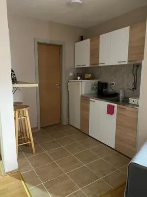 a kitchen with white cabinets and a tile floor at Apartman Stojadinović in Ruma