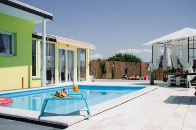 a swimming pool with a table next to a house at Bungalow Lux in Novi Banovci