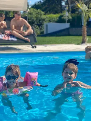 two children in the water in a swimming pool at Bungalow Lux in Novi Banovci