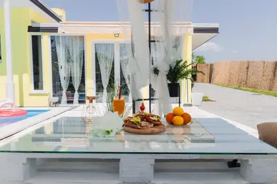 a glass table with a plate of food on a patio at Bungalow Lux in Novi Banovci