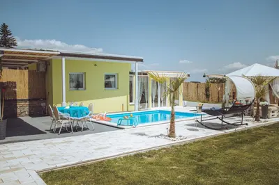 a house with a swimming pool with a table and chairs at Bungalow Lux in Novi Banovci